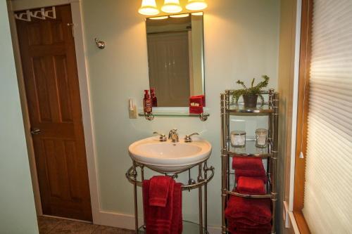 W łazience znajduje się umywalka, lustro i czerwone ręczniki. w obiekcie Simply Serene w mieście Crumpler