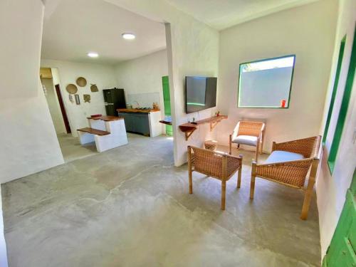 Zimmer mit Stühlen, einem Tisch und einem TV in der Unterkunft ((Casa brisa das águas)) Rota ecológica de milagres in Pôrto de Pedras