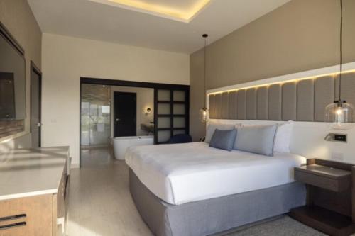 a bedroom with a large white bed and a bathroom at Royalton Hideaway Blue Waters, An Autograph Collection All-Inclusive Resort - Adults Only in Falmouth