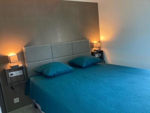 - une chambre avec un lit bleu et 2 oreillers bleus dans l'établissement Village naturiste - Port-Nature 4 coursives vue mer - Le Point G., au Cap d'Agde