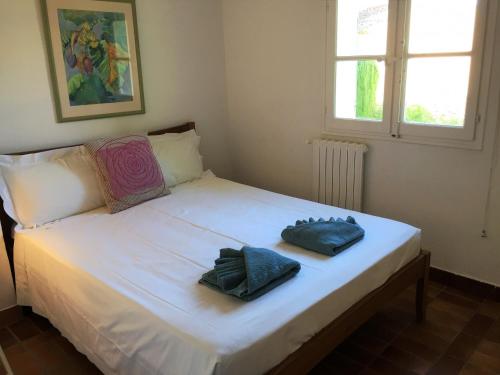 un lit blanc avec deux serviettes dessus dans l'établissement Maison Bleu, à Grimaud