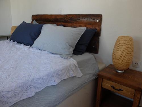 a bedroom with a bed with blue pillows and a table at Kavousi Cottages - O Stavlos in Kavoúsion