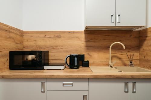 a kitchen counter with a black microwave and a sink at ORSO Rooms & Apartments - LoftAffair Collection in Warsaw