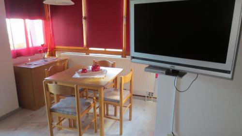 ein Wohnzimmer mit einem Tisch und einem großen TV in der Unterkunft Arberblick - b45689 in Schöfweg