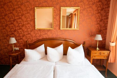 a bedroom with a bed with white pillows and a mirror at Hotel Seestern in Röbel