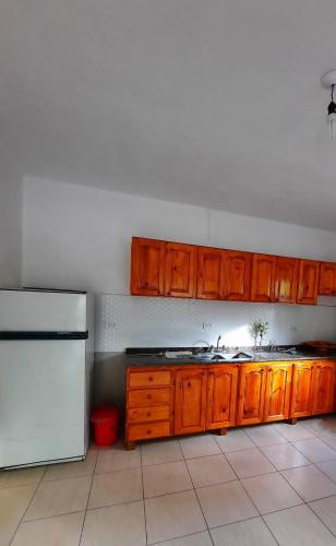 cocina con armarios de madera y nevera blanca en Las talas casa de vacaciones en Santa Florentina