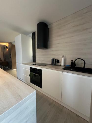 una cucina con armadi bianchi e un forno a piano cottura nero di Zielona Góra Apartament a Jugów