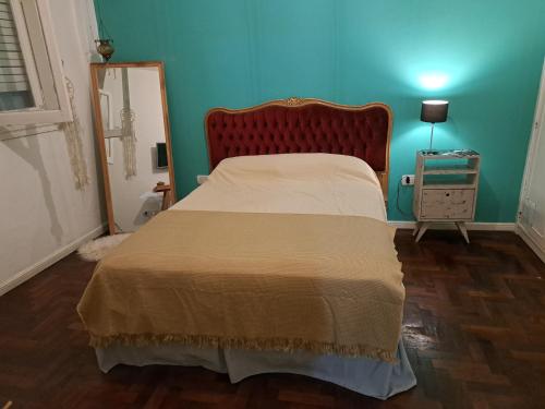 um quarto com uma cama com uma cabeceira vermelha e um espelho em La casita de boedo em Buenos Aires