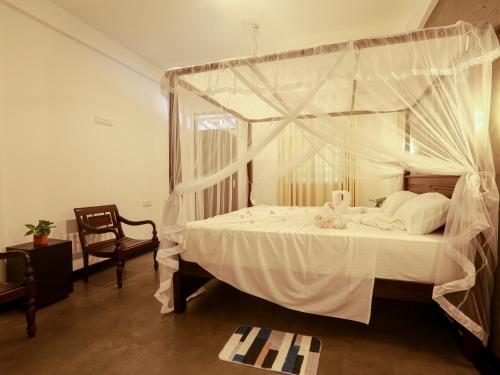 a bedroom with a canopy bed with white sheets and pillows at Sea View Villa in Hikkaduwa