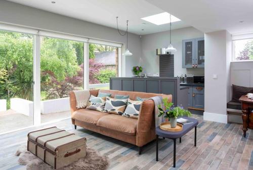 a living room with a brown couch and a kitchen at Garden Rooms @ Drumagosker Rural Retreats in Ardmore