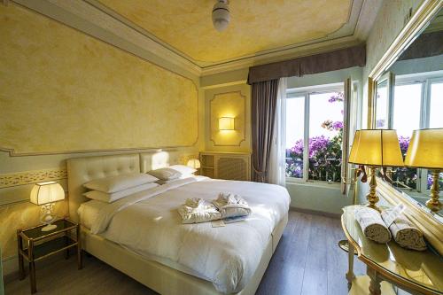 ein Schlafzimmer mit einem großen weißen Bett und einem Fenster in der Unterkunft Hotel Villa Florida Suites & Suite Apartments in Gardone Riviera