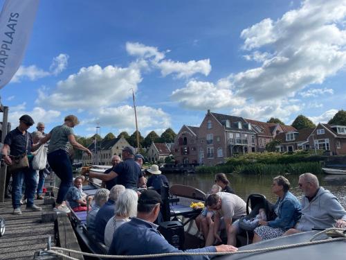 a group of people sitting on a boat on the water at Tiny house - optioneel met hottub in Dokkum