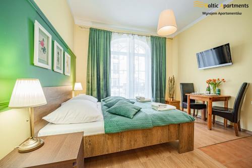 sypialnia z łóżkiem, biurkiem i telewizorem w obiekcie Baltic Apartments - Apartamenty Korony Piastów w Świnoujściu
