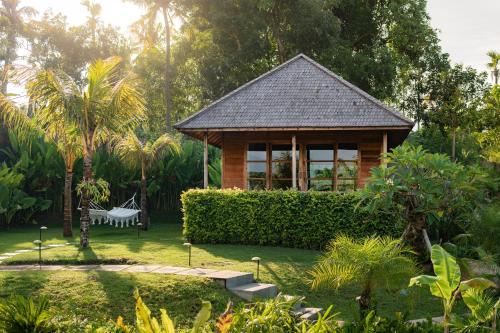 a wooden gazebo with a bench in a garden at East Bali Volcano View Resort & Spa - Adults Only Area in Karangasem