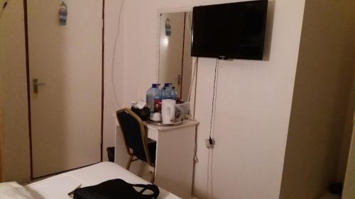 Zimmer mit einem Bett und einem TV an einer Tür in der Unterkunft Palm Tree Guest House in Manzini