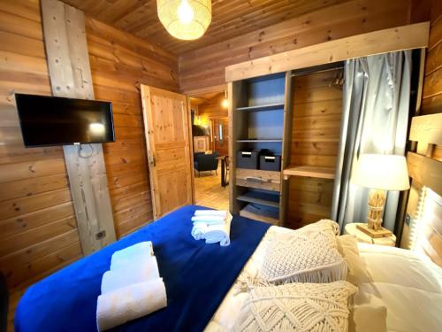 LE FISHING LODGE Chalet en bois avec bain nordique في لابريس: غرفة نوم بسرير ازرق في غرفة خشبية