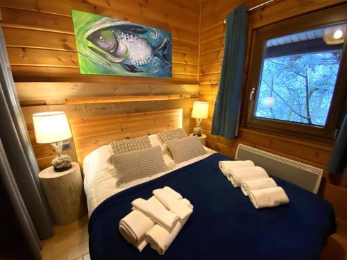 une chambre avec un lit bleu avec des serviettes dessus dans l'établissement LE FISHING LODGE Chalet en bois avec bain nordique, à La Bresse