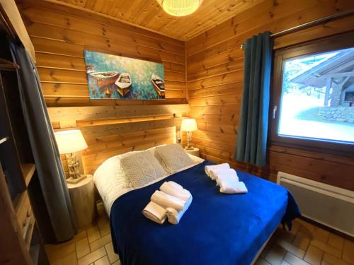 une chambre avec un lit bleu avec des serviettes dessus dans l'établissement LE FISHING LODGE Chalet en bois avec bain nordique, à La Bresse