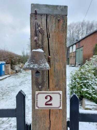 een houten paal met een bel op een hek bij Le Petit Refuge 