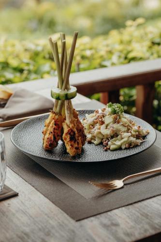 a plate with some food on a wooden table at East Bali Volcano View Resort & Spa - Adults Only Area in Karangasem