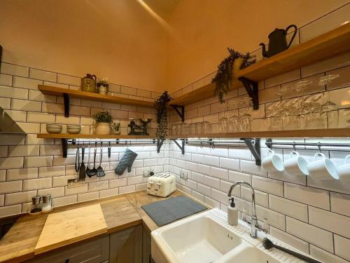 a kitchen with a sink and a white tiled wall at City Centre Loft Apartment in Stalybridge