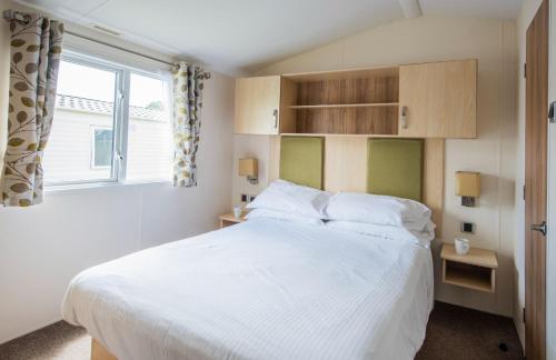 a bedroom with a large white bed and a window at Sandaway Holiday Park in Combe Martin