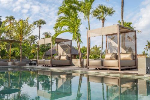 einen Pool mit Chaiselongue und Palmen in der Unterkunft East Bali Volcano View Resort & Spa - Adults Only Area in Karangasem