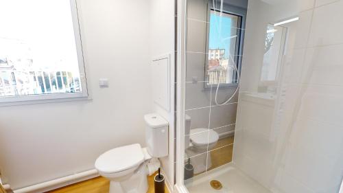 a white bathroom with a toilet and a shower at Studio 8 in Fontainebleau