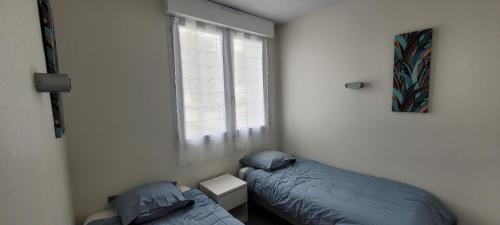 une chambre avec deux lits et une fenêtre dans l'établissement T3 “Belle-île“- 50 m de la plage de Fort Bloqué/Ploemeur, à Ploemeur