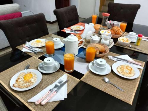 a breakfast table with breakfast foods and orange juice at Hotel Hoskins Talara cerca centro, refinería in Talara