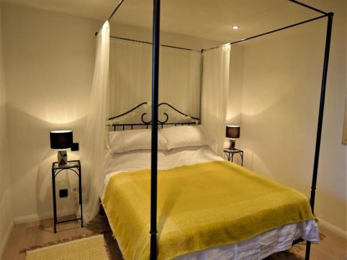 a bedroom with a canopy bed with a yellow blanket at Hares Barn in Trowbridge