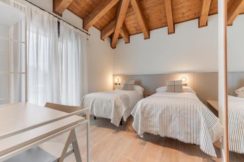 Duas camas num quarto com tectos em madeira e uma mesa em Casa Lambda em Jaca