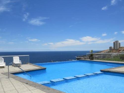 uma grande piscina com vista para o oceano em Hermoso y comodo depto en Cochoa em Viña del Mar
