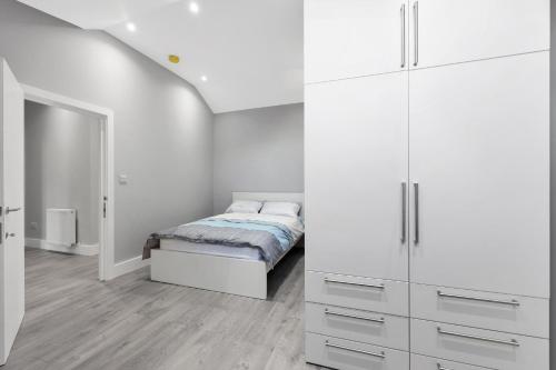 um quarto com uma cama e armários brancos em Your Cosy Stay Modern 2 Double Bedroom Flat Fully Furnished - 5 Mins walk to Stn em Londres