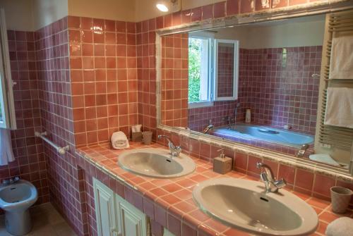 La salle de bains est pourvue de carrelage rouge, de deux lavabos et d'une baignoire. dans l'établissement Chambre d'hôtes le bois des combes chambre 