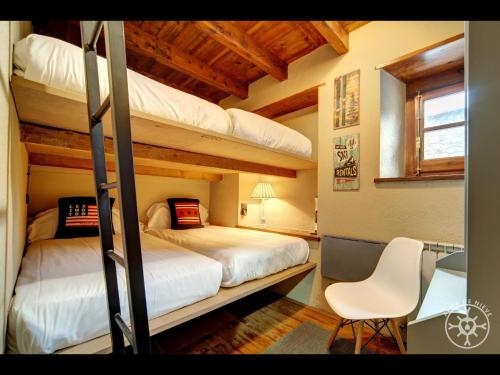 a bedroom with two bunk beds and a chair at CASA SAUTARETH de Alma de Nieve in Tredós