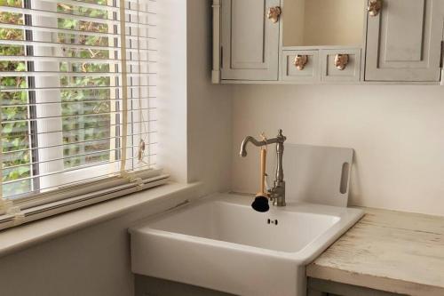 a white sink in a bathroom with a window at Beautiful 1 bed annex, near beach and shops in Iford