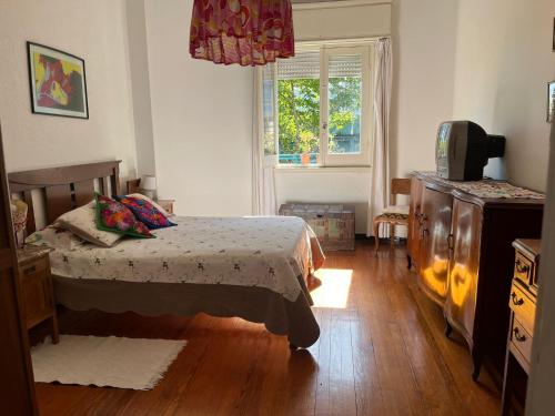 een slaapkamer met een bed, een dressoir en een raam bij en el corazón del Barrio Sur in Montevideo