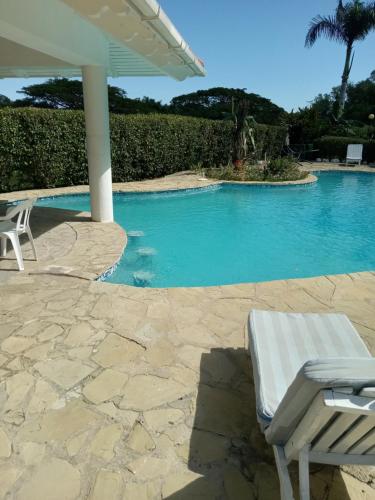 a swimming pool with a white chair and an umbrella at Tropical Optimal Tropicana Sur in Sosúa