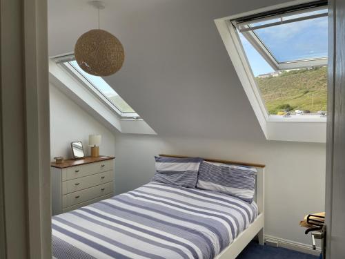 a bedroom with a bed and a window at Driftwood in Porthtowan