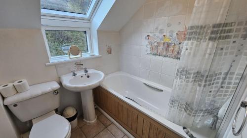 a bathroom with a toilet and a sink and a shower at Driftwood in Porthtowan