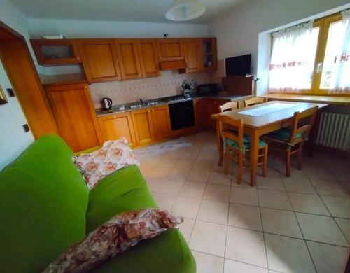a living room with a green couch and a kitchen at Appartamento Daniela Dolomiti. in Auronzo di Cadore