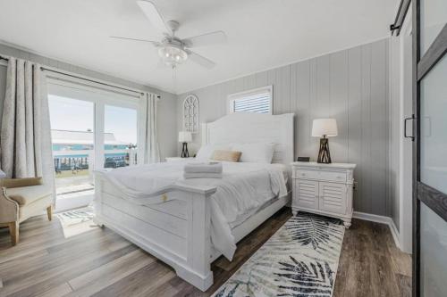 a white bedroom with a bed and a window at The Blue Bungalow St. George Island in St. George Island