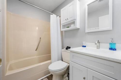 Baño blanco con aseo y lavamanos en The Blue Bungalow St. George Island, en St. George Island