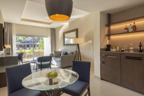 a living room with a glass table and blue chairs at Royalton Hideaway Blue Waters, An Autograph Collection All-Inclusive Resort - Adults Only in Falmouth