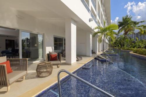 a swimming pool in a building with chairs and tables at Royalton Hideaway Blue Waters, An Autograph Collection All-Inclusive Resort - Adults Only in Falmouth