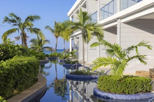 a building with palm trees and water in front of it at Royalton Hideaway Blue Waters, An Autograph Collection All-Inclusive Resort - Adults Only in Falmouth