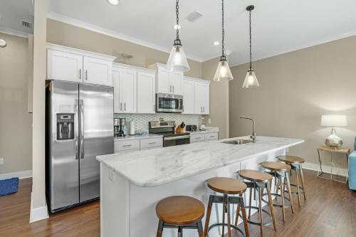 a kitchen with white cabinets and a large island with bar stools at The Nautilus in Gulf Shores