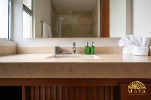 Un mostrador de baño con un lavabo y un espejo. en NHOA 211B Lux 1BR Condo Pool View in Aldea Zama, en Tulum