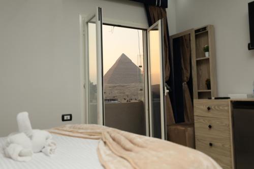 a bedroom with a bed with a view of the pyramid at Capital Of Pyramids Hotel in Cairo